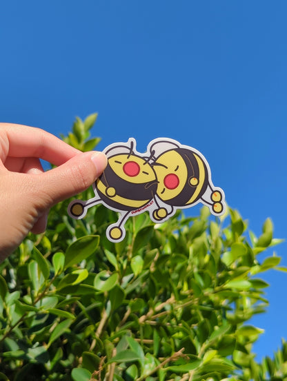 a person's hand holding up a sticker of two cartoon bumble bees taking a nap together