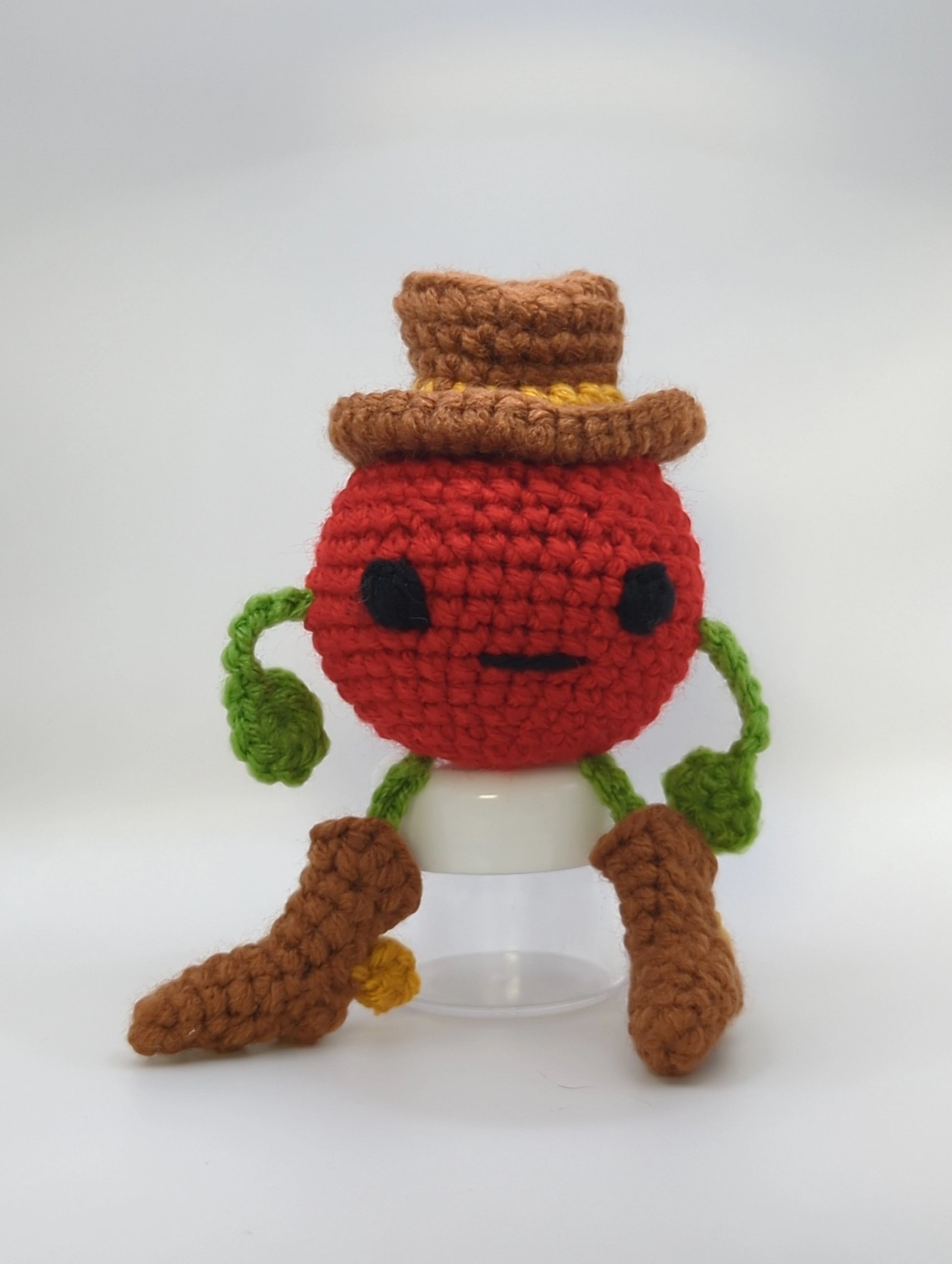 crocheted soft toy of a tomato dressed like a cowboy