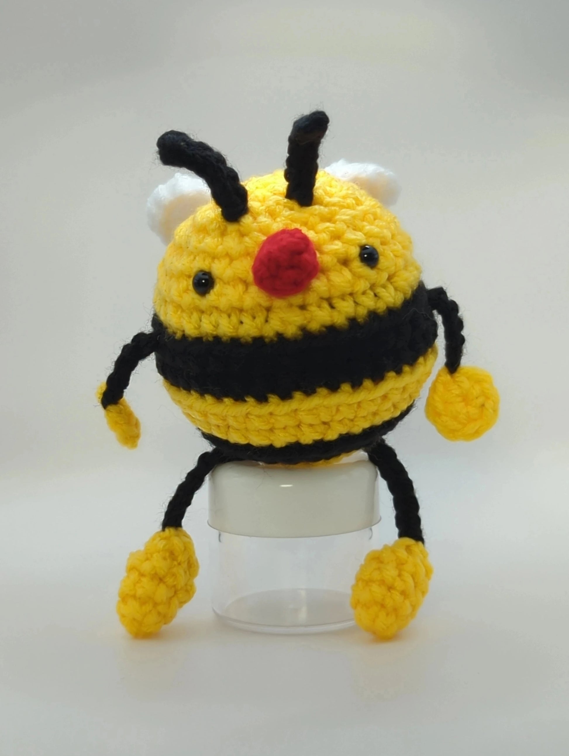 Crocheted soft toy of a cartoon bumble bee against a white backdrop