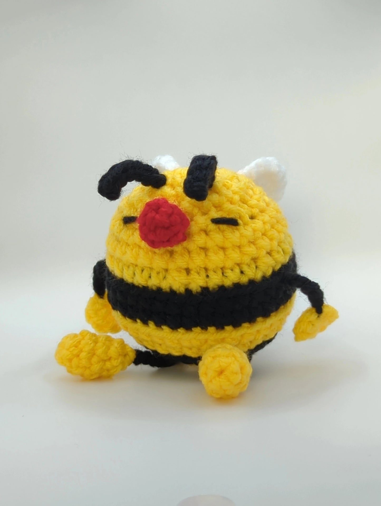 crocheted soft toy of a cartoon bumble bee taking a nap