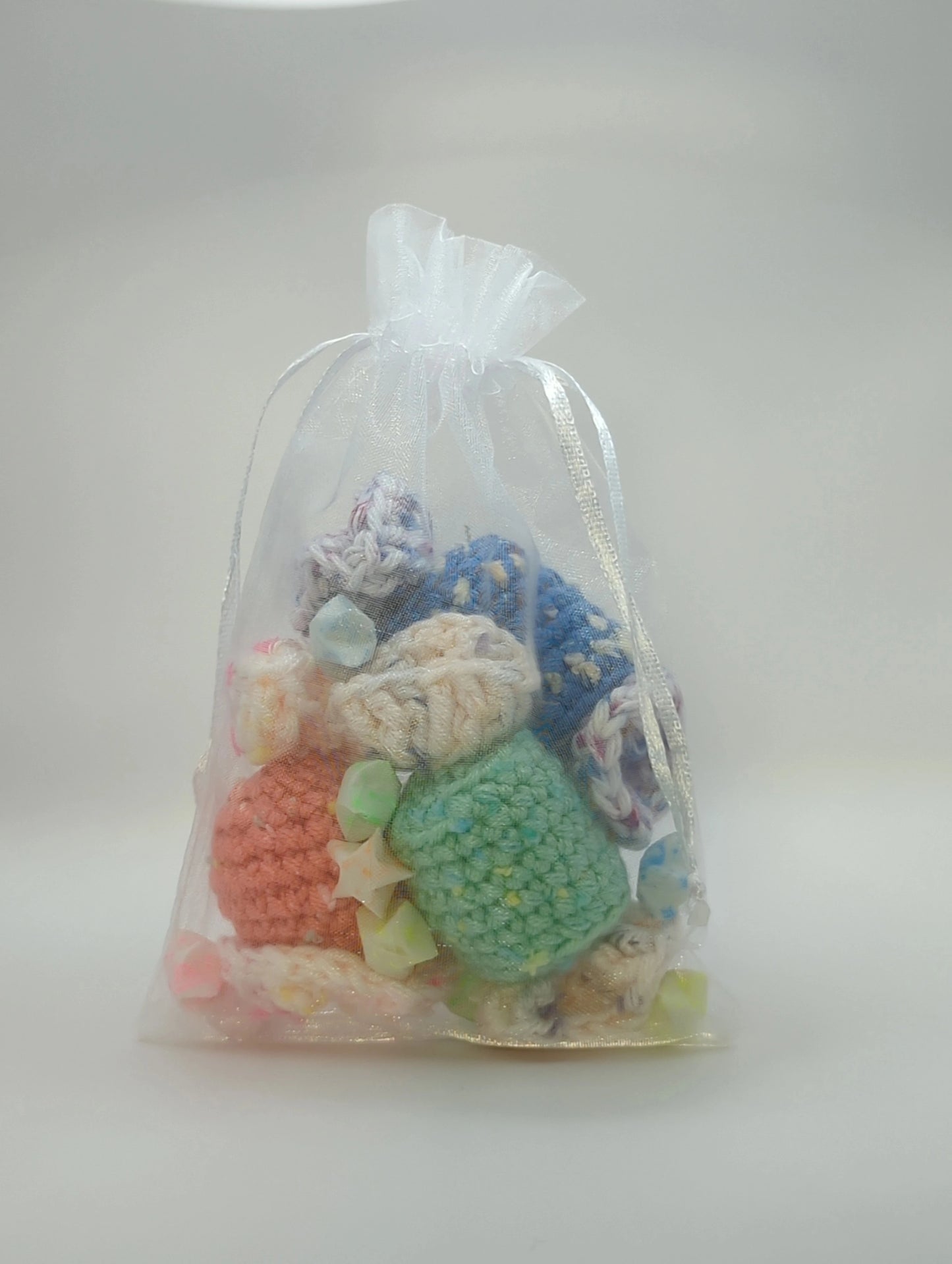 an organza bag containing paper stars and crocheted candy pieces