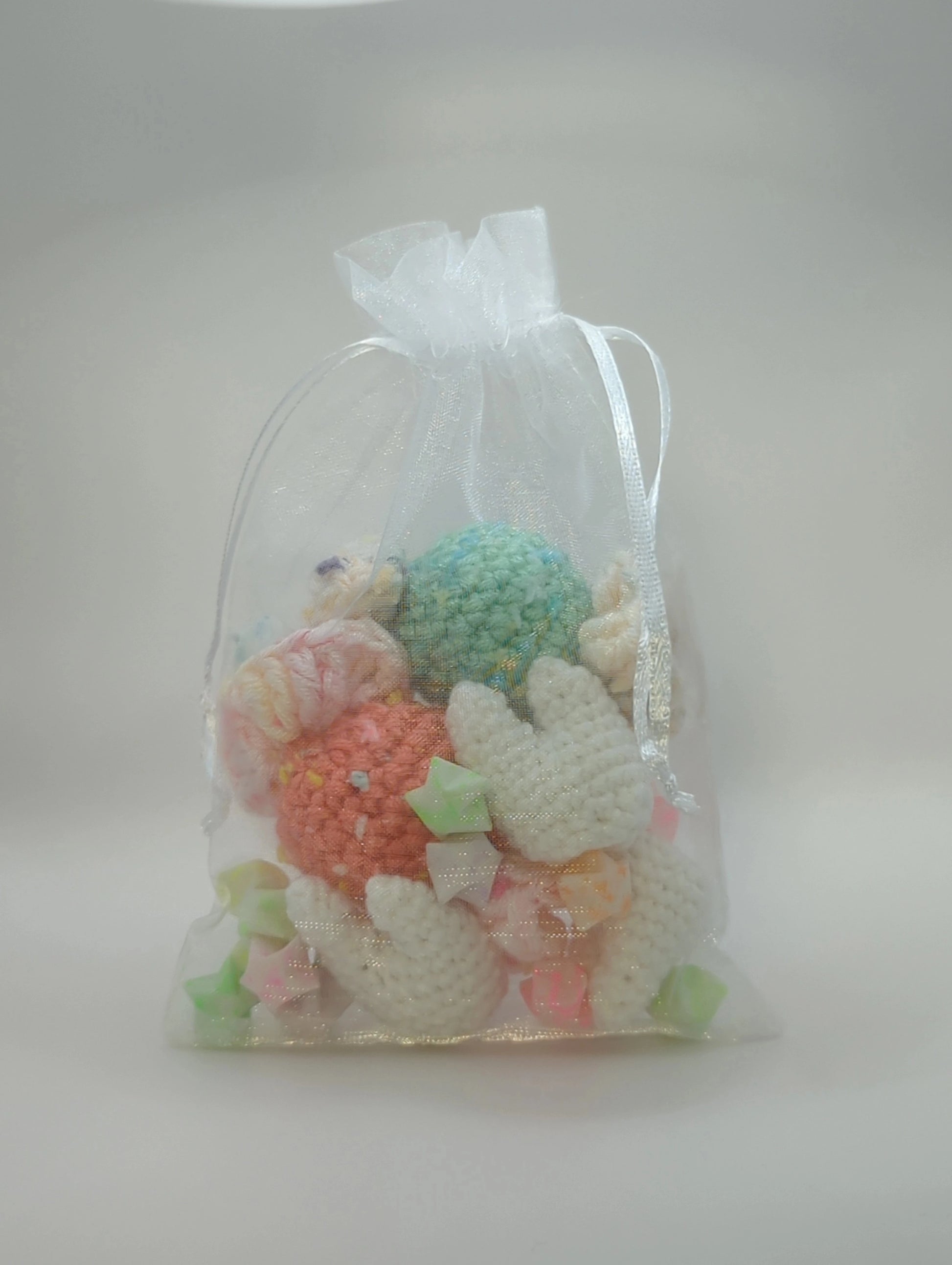 an organza bag containing paper stars and crocheted candy pieces and teeth