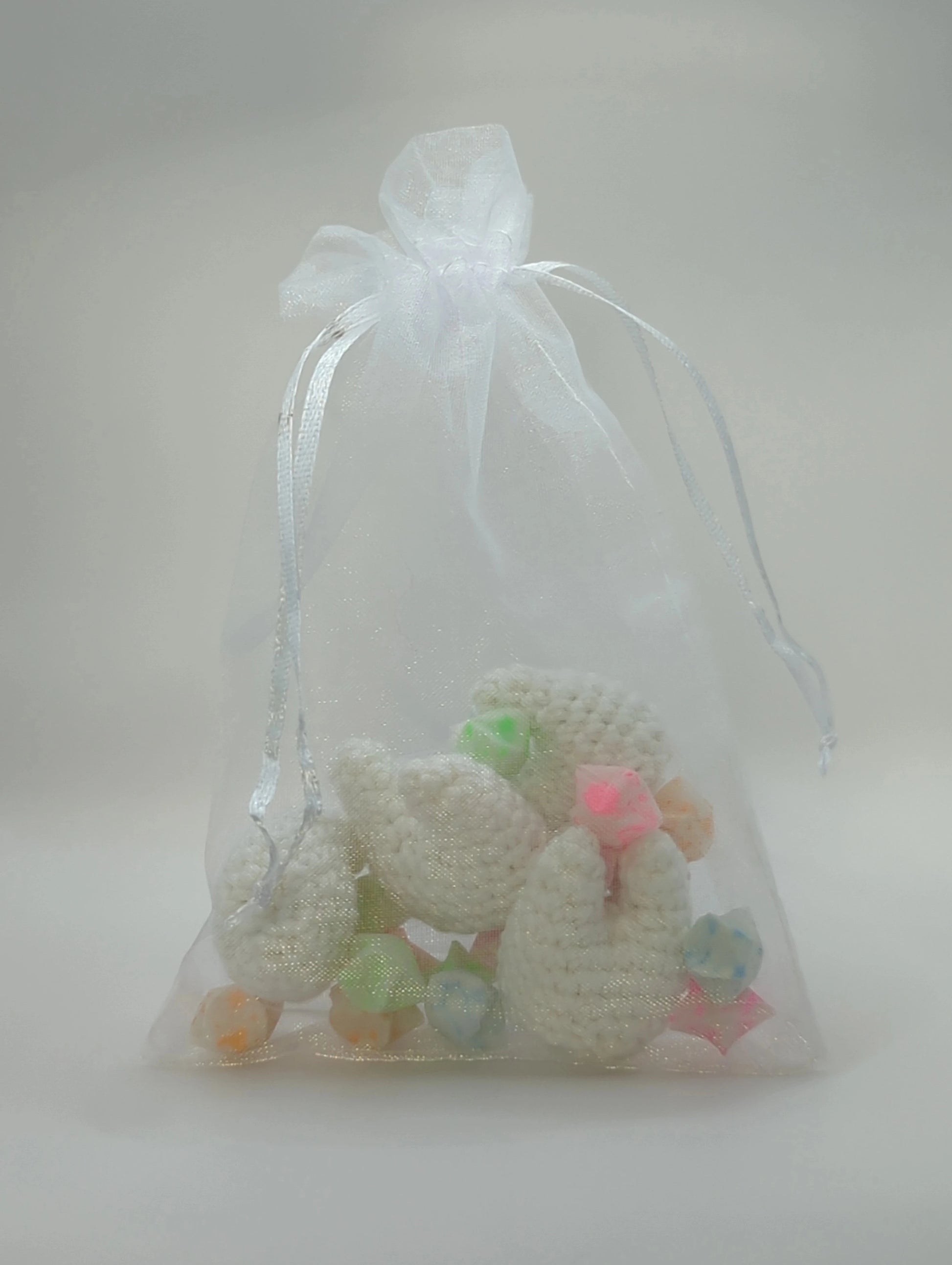 an organza bag containing paper stars and crocheted teeth