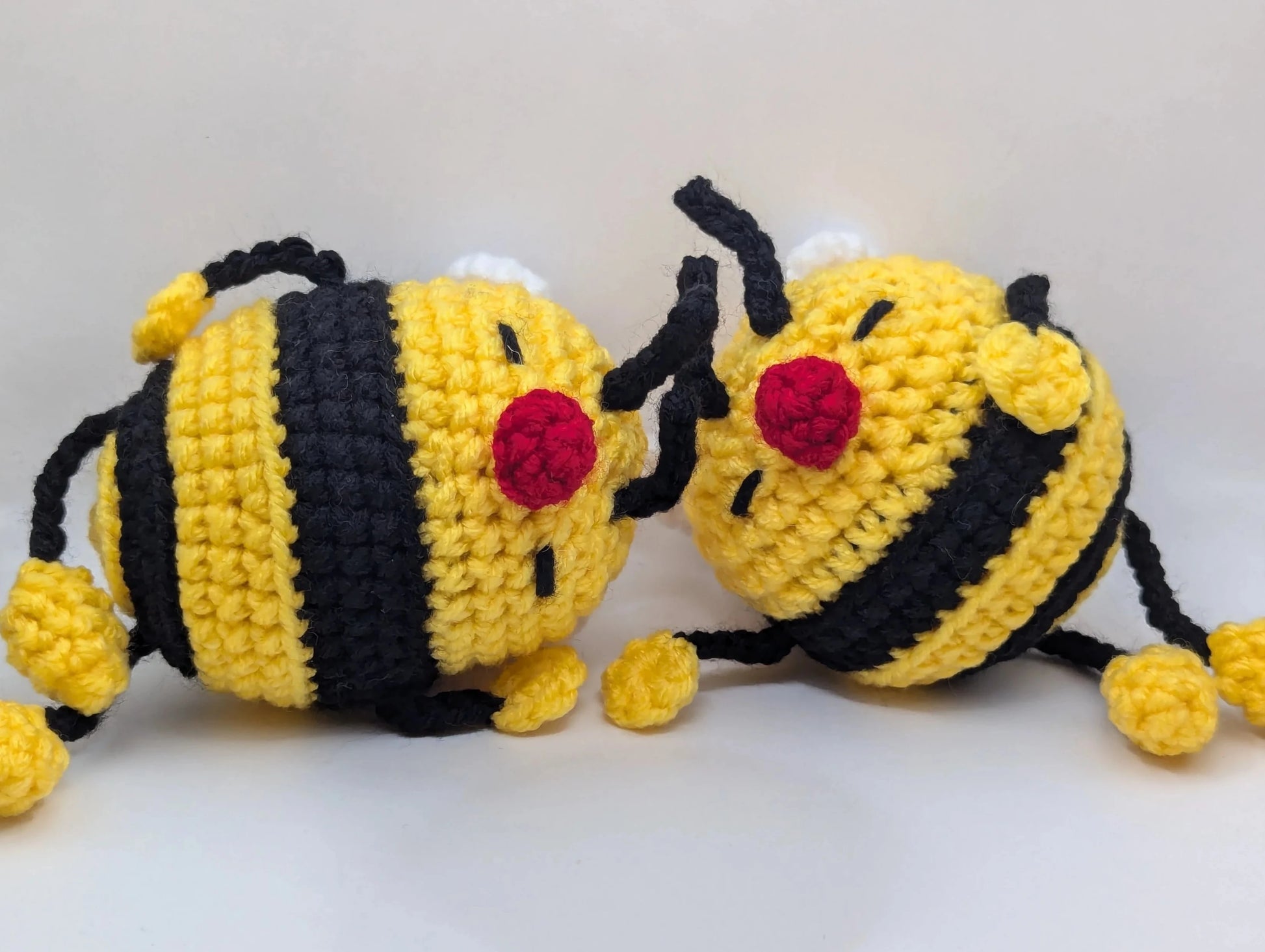 two crocheted soft toys of a cartoon bumble bee taking a nap